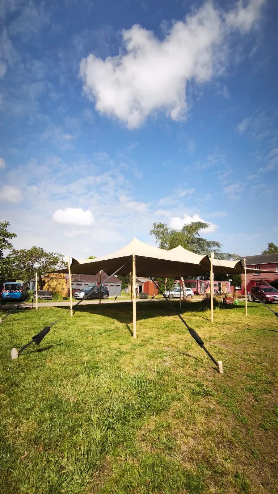 Tente stretch beige montée sur une pelouse devant des bâtiments