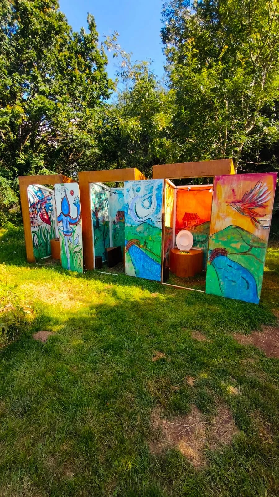 Cabines de toilettes sèches aux portes colorées dans le jardin de L’Escampette
